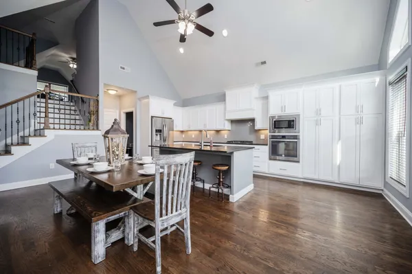 a dining room with stainless steel appliances kitchen island granite countertop a table chairs and a refrigerator