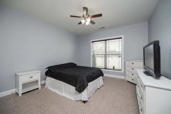 a spacious bedroom with a bed and a flat tv screen on a dresser