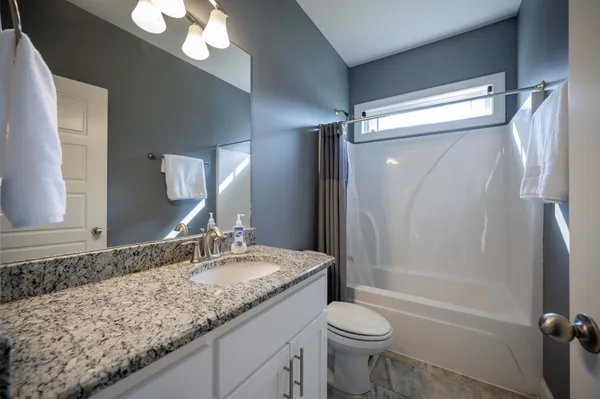 a bathroom with a granite countertop sink toilet and shower