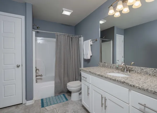 a bathroom with a granite countertop sink toilet a mirror a vanity and shower