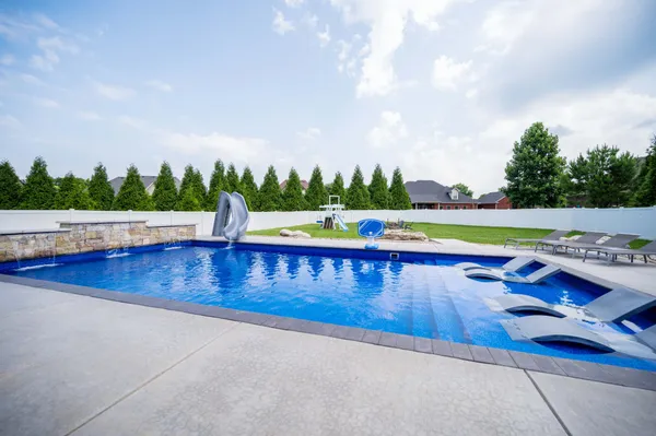a view of swimming pool with lounge chair and trees in the background