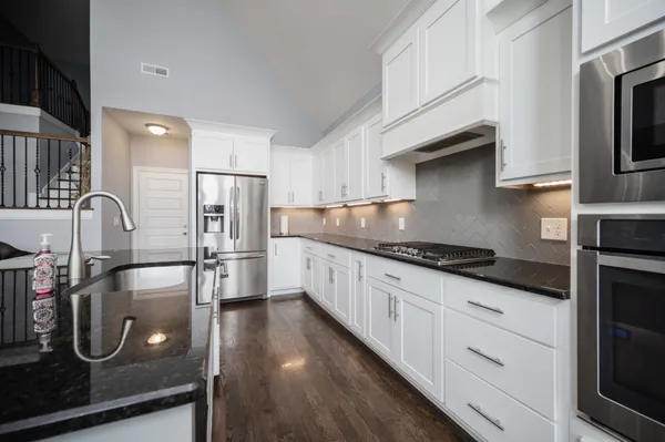 a kitchen with stainless steel appliances granite countertop a sink a stove and a refrigerator