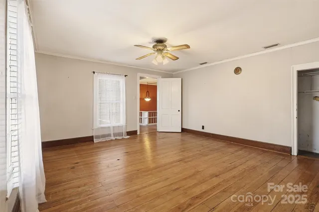 an empty room with wooden floor ceiling fan and window