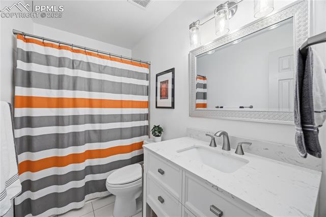 2135 Glenhill Road Colorado Springs, CO 80906 - Photo 31 of 50 Full bath with curtained shower, vanity, and light tile patterned floors
