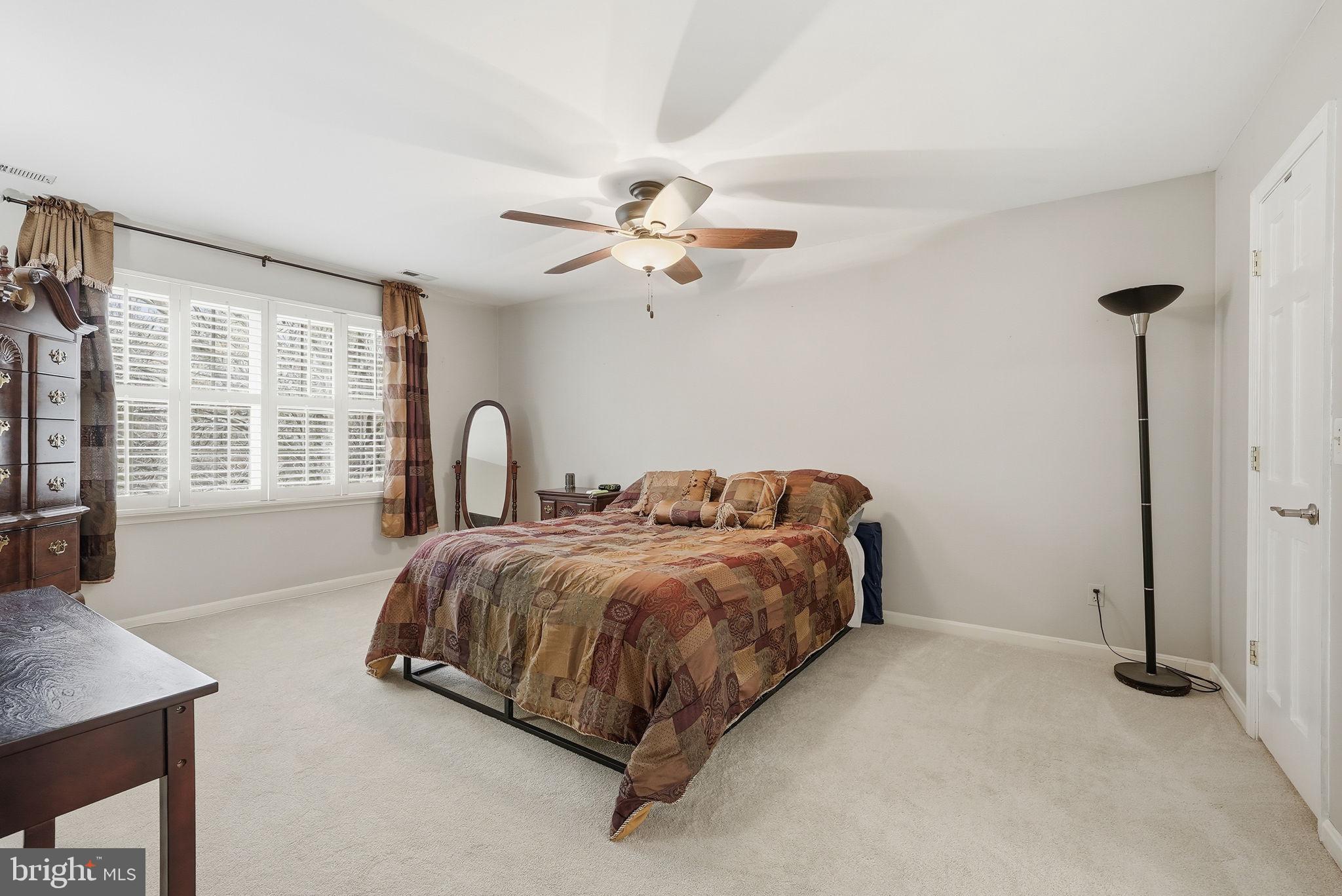 140 Hoile Lane Huntingtown, MD 20639 - Photo 20 of 44 a spacious bedroom with a bed chandelier and a window