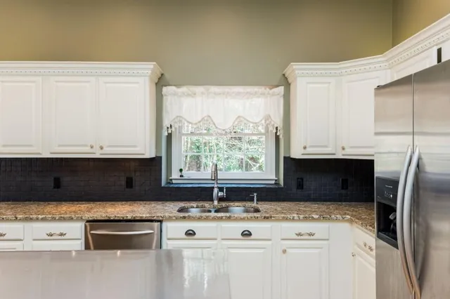 a kitchen with stainless steel appliances granite countertop a stove a sink a refrigerator and white cabinets