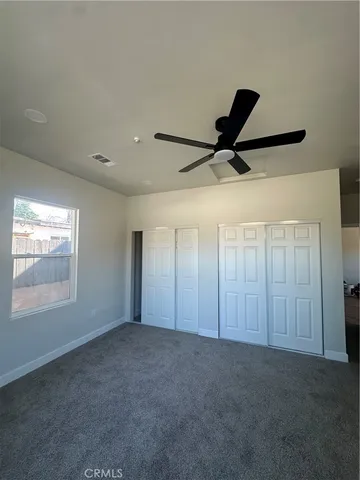 a view of a livingroom with a ceiling fan & windows
