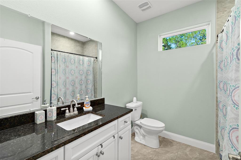 6 Wavecrest Place Palm Coast, FL 32164 - Photo 15 of 22 a bathroom with a granite countertop sink a toilet and a mirror