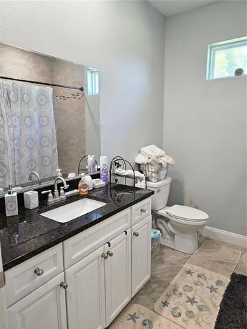 a bathroom with a granite countertop toilet sink and mirror
