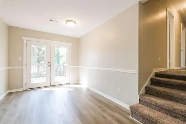 a view of an empty room with wooden floor and windows