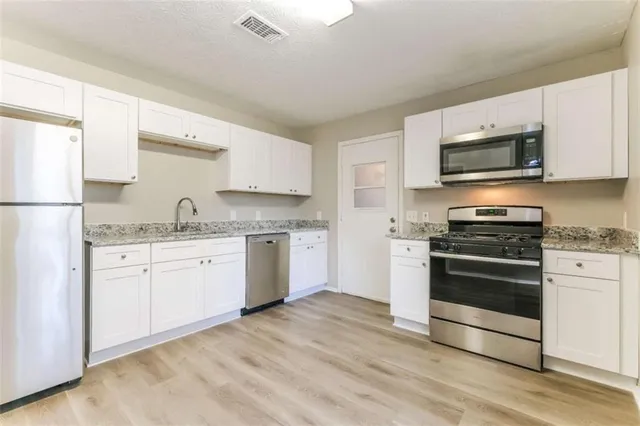 a kitchen with granite countertop a refrigerator and a stove top oven