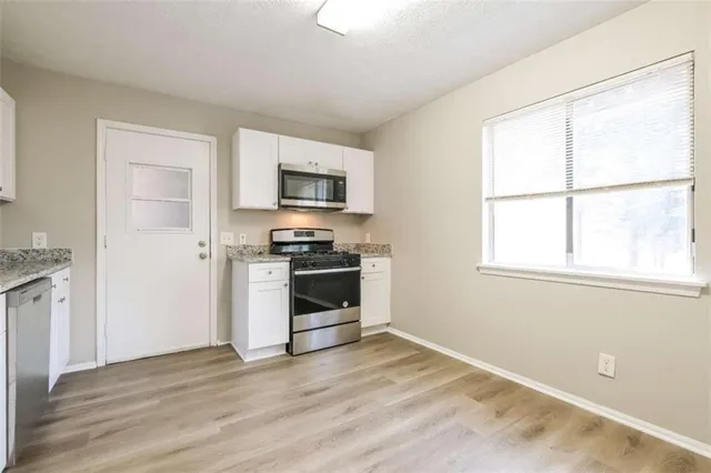 a kitchen with granite countertop a stove a sink and a microwave