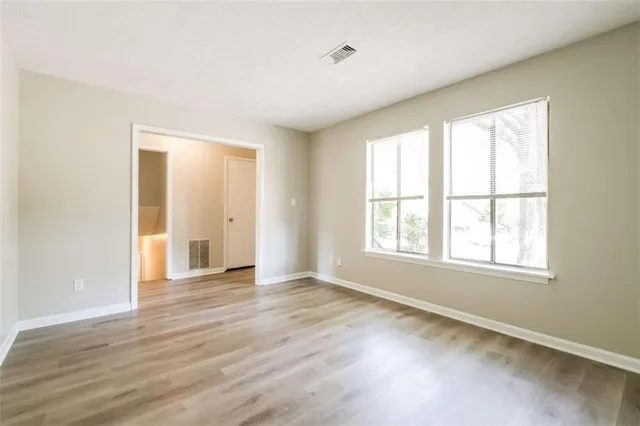 an empty room with wooden floor and windows