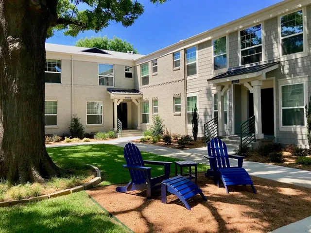 a view of a white house with a yard garden and outdoor seating
