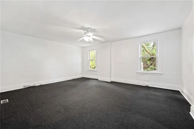 an empty room with a window and a ceiling fan