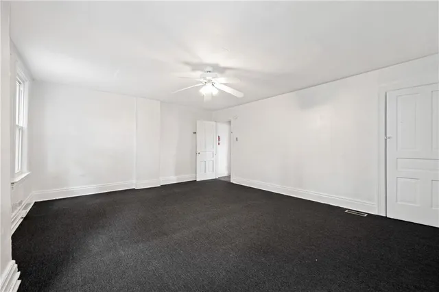 an empty room with a ceiling fan and a window