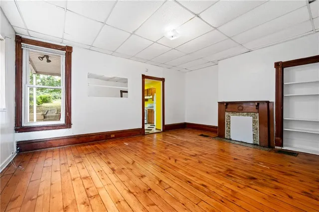a view of an empty room with window and wooden floor