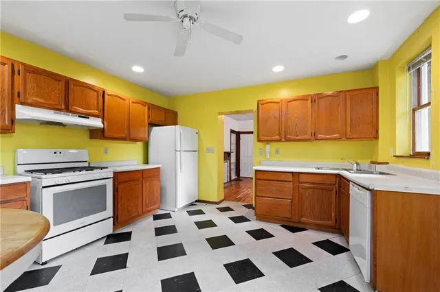 a kitchen with a stove a sink a refrigerator a window and cabinets