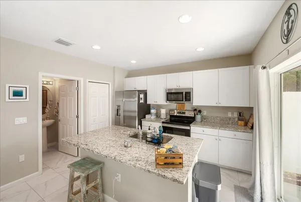 a kitchen with stainless steel appliances kitchen island granite countertop a sink refrigerator and cabinets