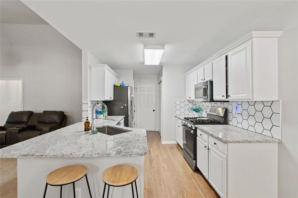 2907 Albright Commons Kennesaw, GA 30144 - Photo 9 of 35 a kitchen with granite countertop a sink chairs and cabinets