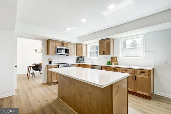 a large kitchen with stainless steel appliances a stove a sink a oven a dining table and chairs