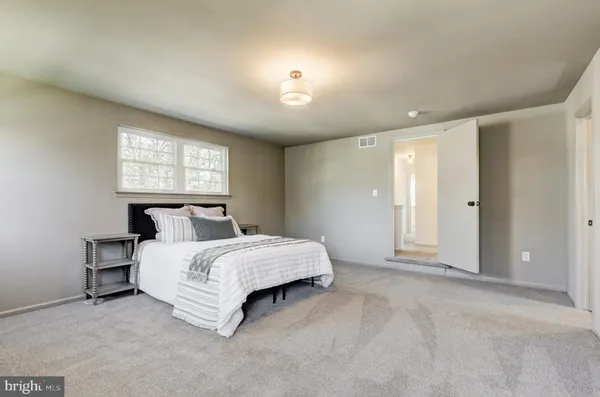 a spacious bedroom with a bed and a lamp