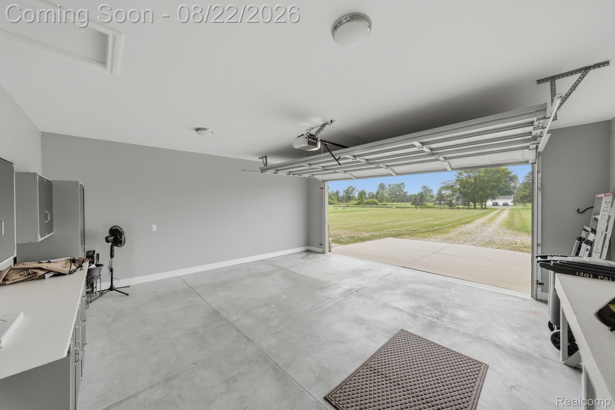 1301 Palms Road Columbus, MI 48063 - Photo 44 of 51 Concrete floor garage with an automatic overhead door, overhead lighting, built-in cabinetry, and a workbench