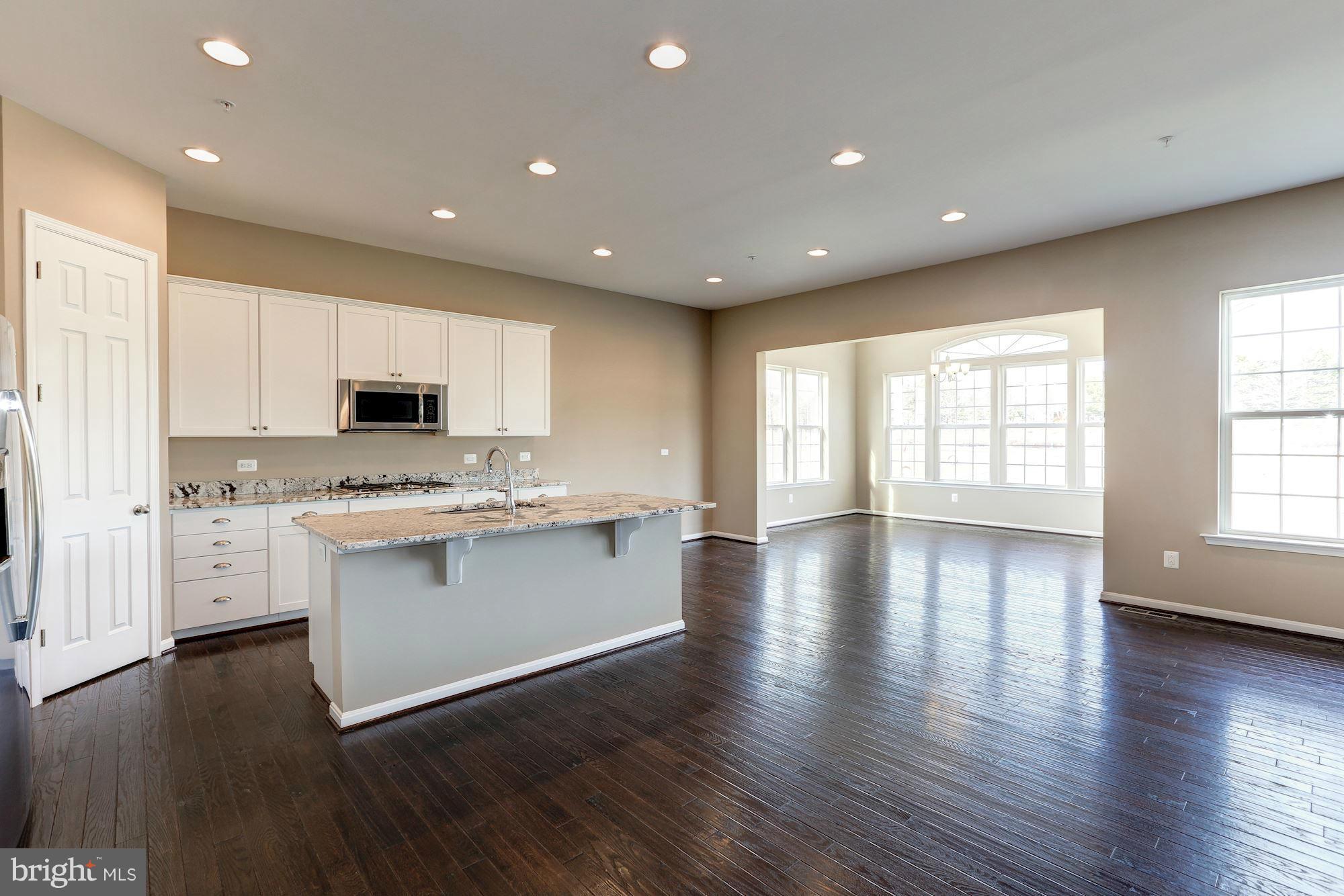 925 Lindley Road Frederick, MD 21701 - Photo 10 of 30 a large kitchen with stainless steel appliances granite countertop a stove top oven a sink and white cabinets with wooden floor next to windows