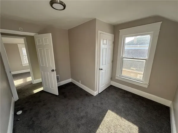a view of an empty room with closet and a window
