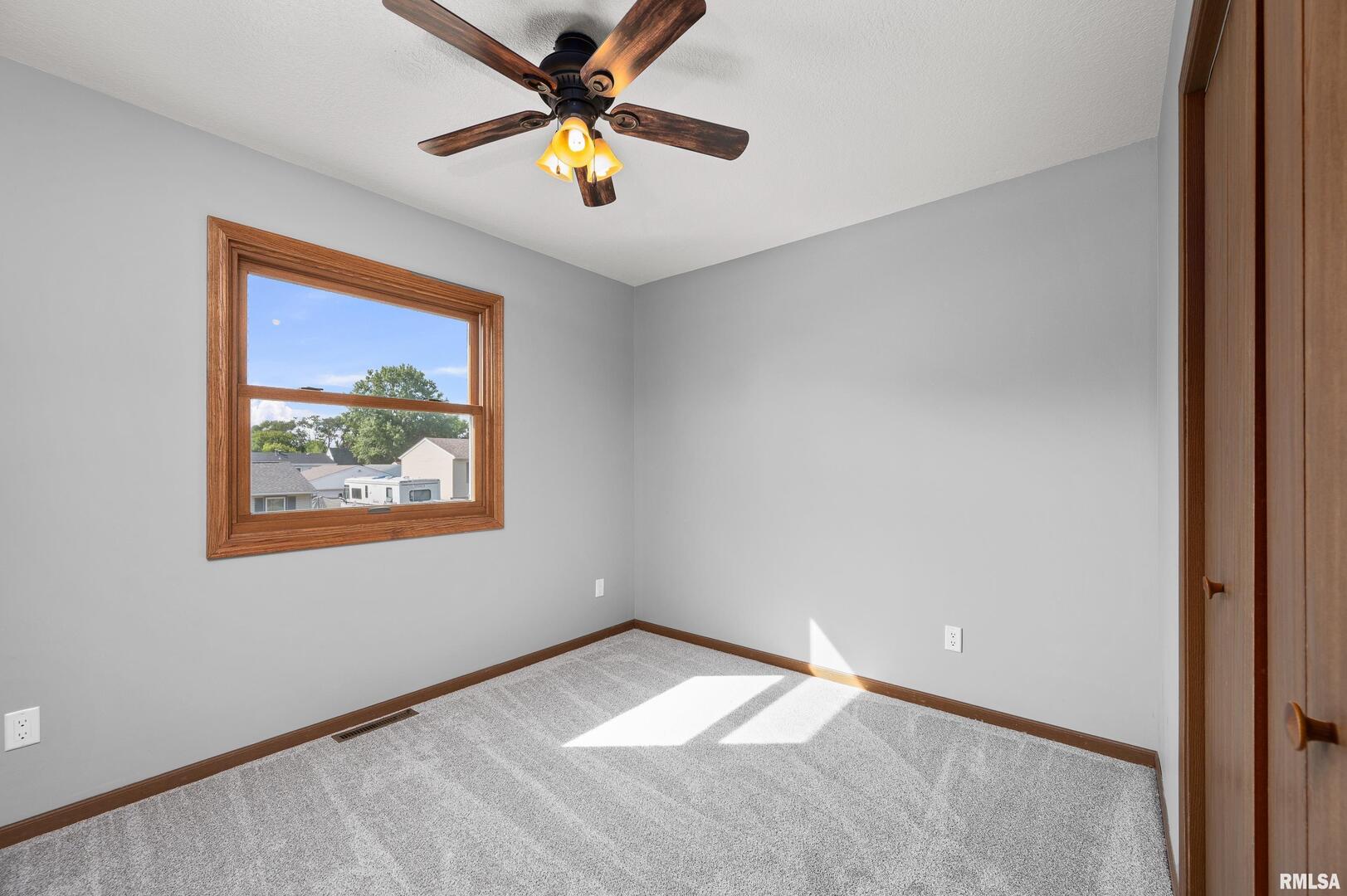 916 Ash Drive Colona, IL 61241 - Photo 15 of 38 an empty room with a window and a fan