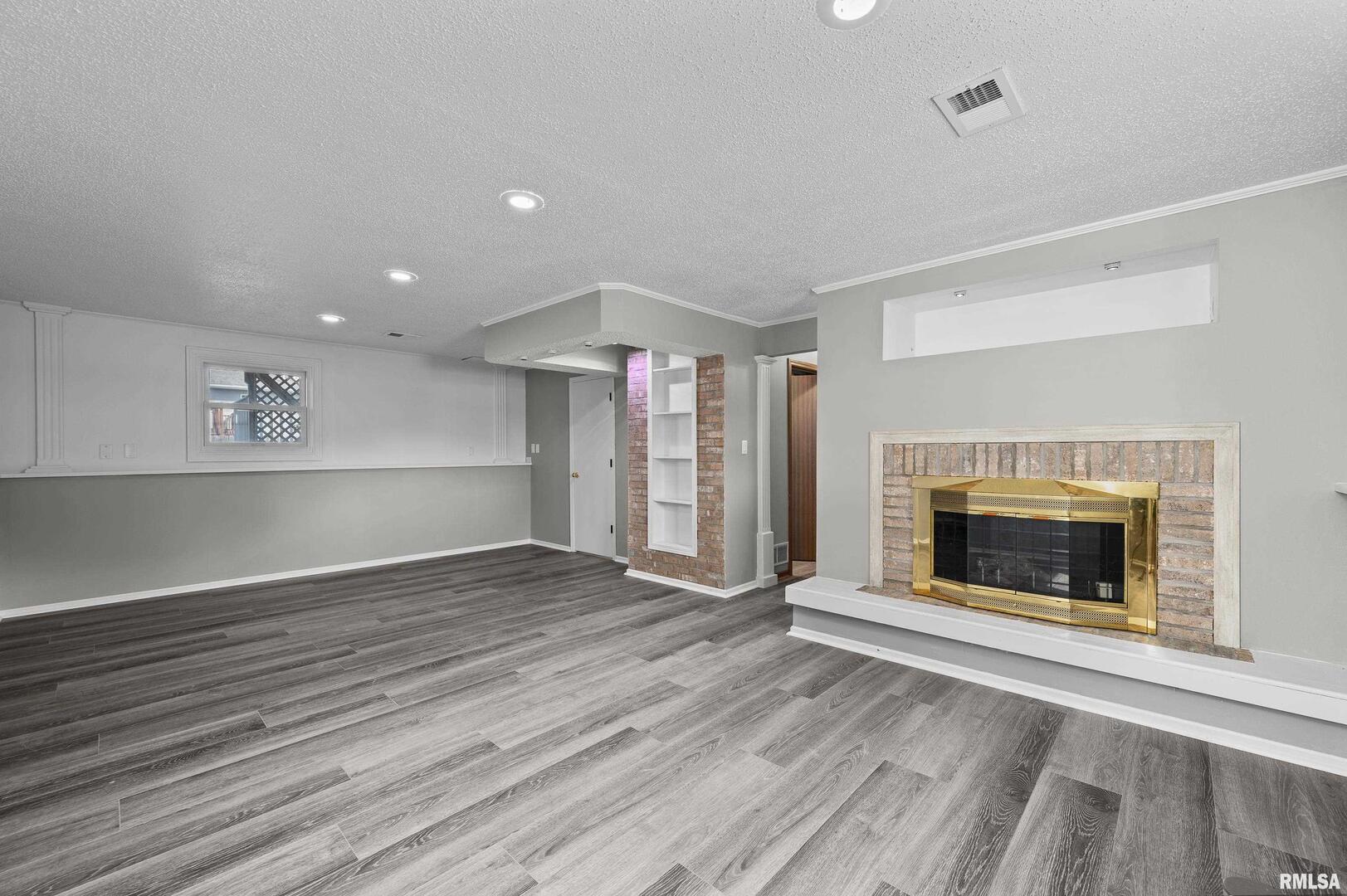 916 Ash Drive Colona, IL 61241 - Photo 23 of 38 an empty room with wooden floor fireplace and windows