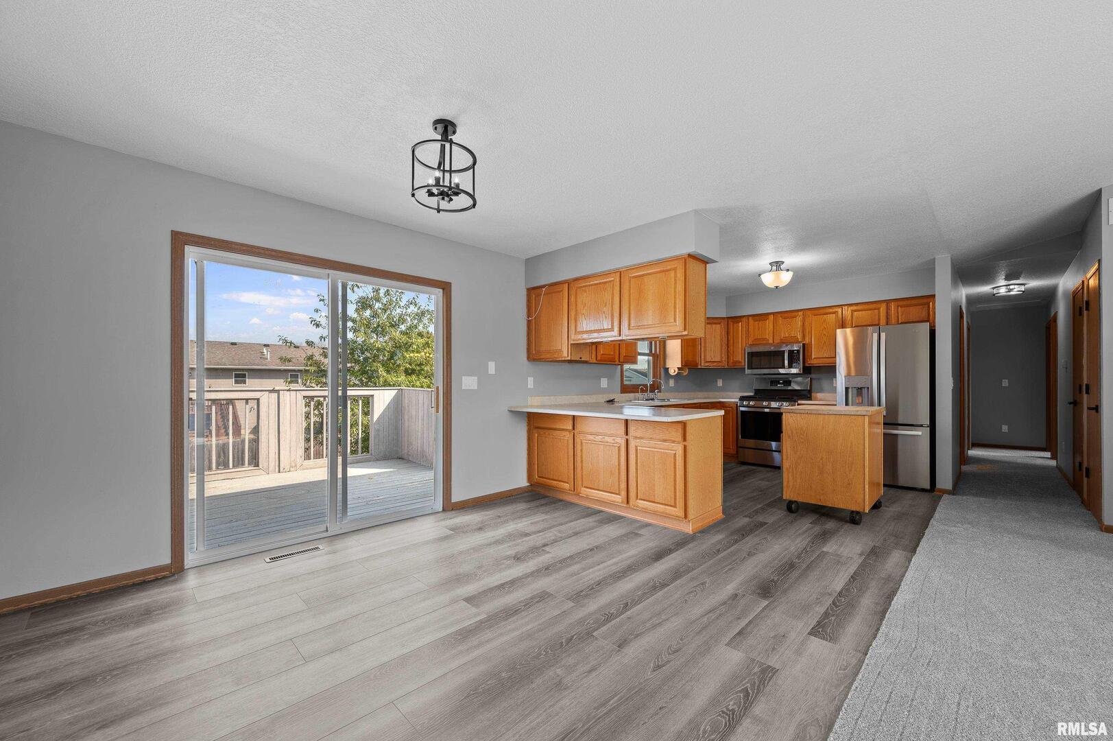 916 Ash Drive Colona, IL 61241 - Photo 7 of 38 a open kitchen with granite countertop a stove top oven a sink and a large window