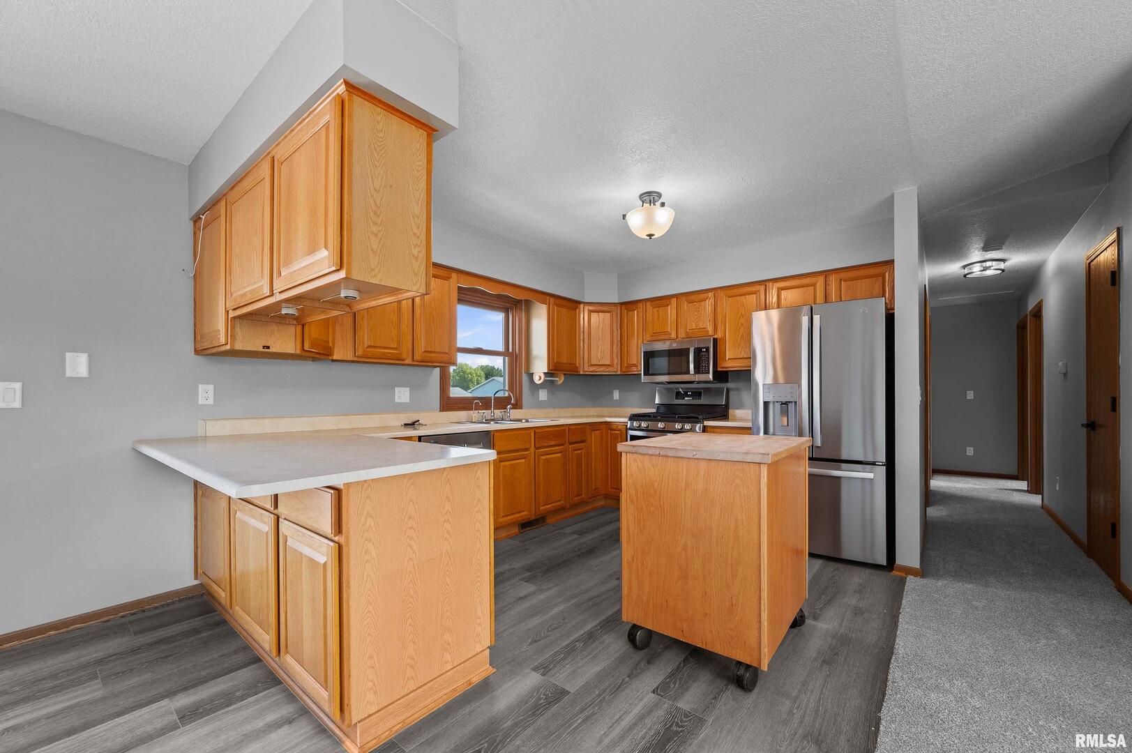 916 Ash Drive Colona, IL 61241 - Photo 9 of 38 a kitchen with stainless steel appliances granite countertop a refrigerator a sink dishwasher a stove and white countertops with wooden floor
