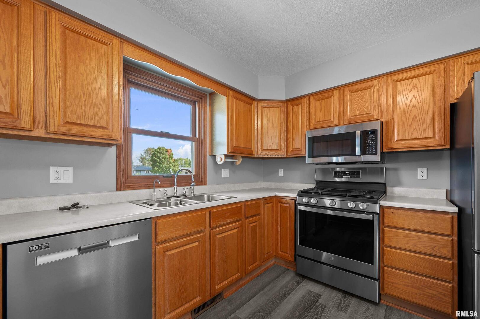 916 Ash Drive Colona, IL 61241 - Photo 10 of 38 a kitchen with stainless steel appliances granite countertop wooden cabinets a stove a sink and a window