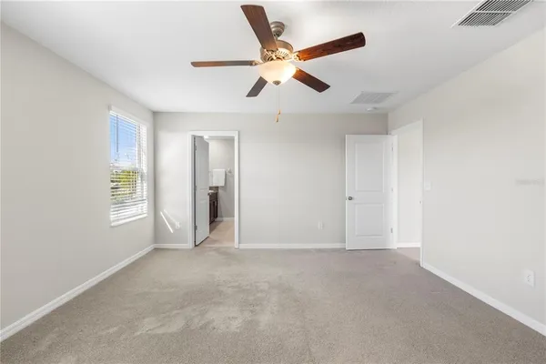 an empty room with a window and a fan