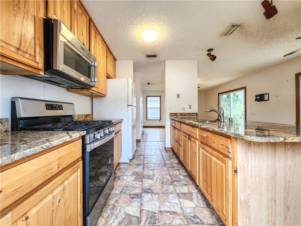 233 13th Street Southwest Vero Beach, FL 32962 - Photo 2 of 20 a large kitchen with stainless steel appliances granite countertop a large stove a sink dishwasher and cabinets with wooden floor