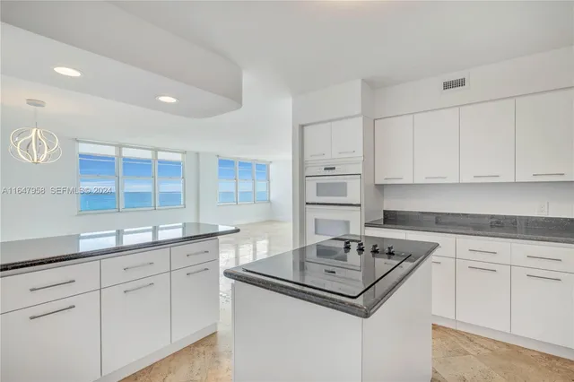 a kitchen with granite countertop a sink cabinets and stainless steel appliances