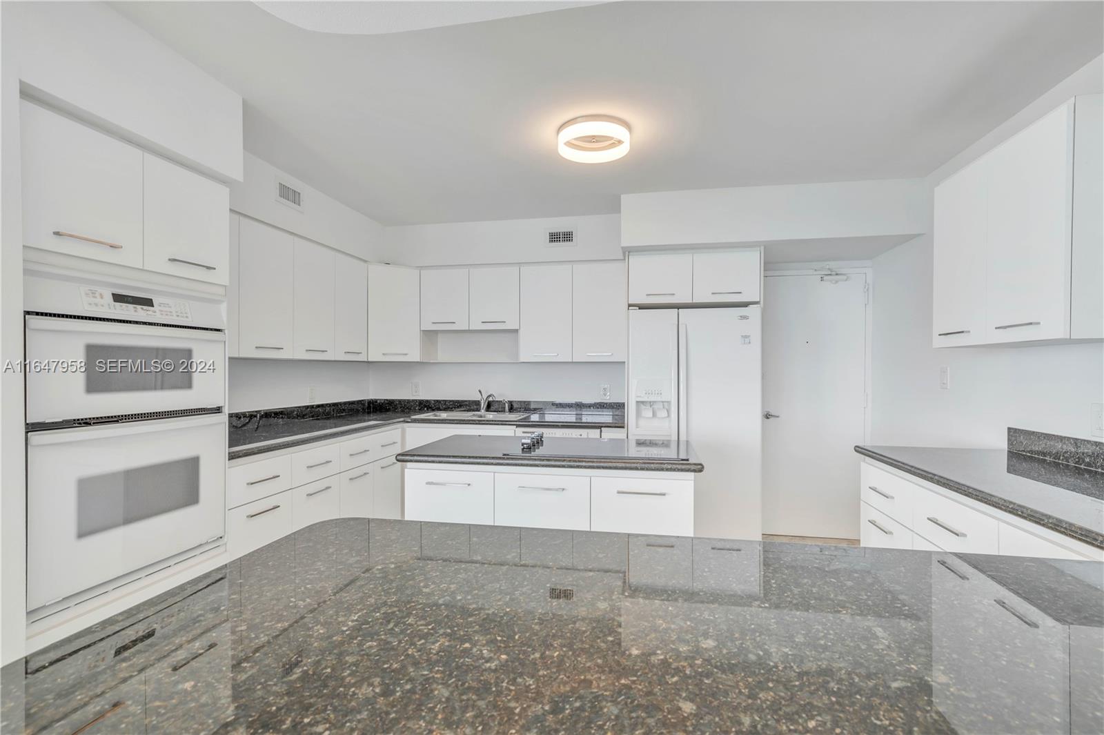 5151 Collins Avenue, Unit 1627 Miami Beach, FL 33140 - Photo 12 of 28 a kitchen with stainless steel appliances granite countertop a stove a sink and a refrigerator
