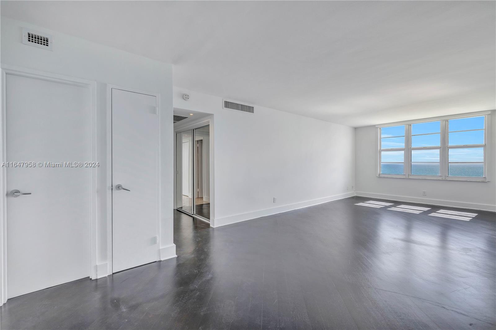 5151 Collins Avenue, Unit 1627 Miami Beach, FL 33140 - Photo 19 of 28 a view of an empty room with wooden floor and a window