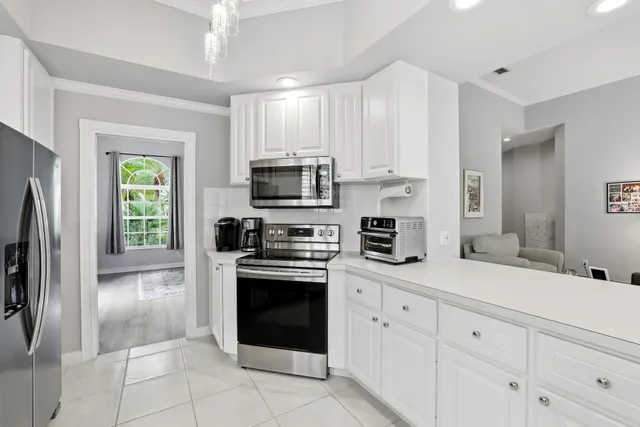 a kitchen with stainless steel appliances granite countertop a refrigerator a stove a sink and white cabinets