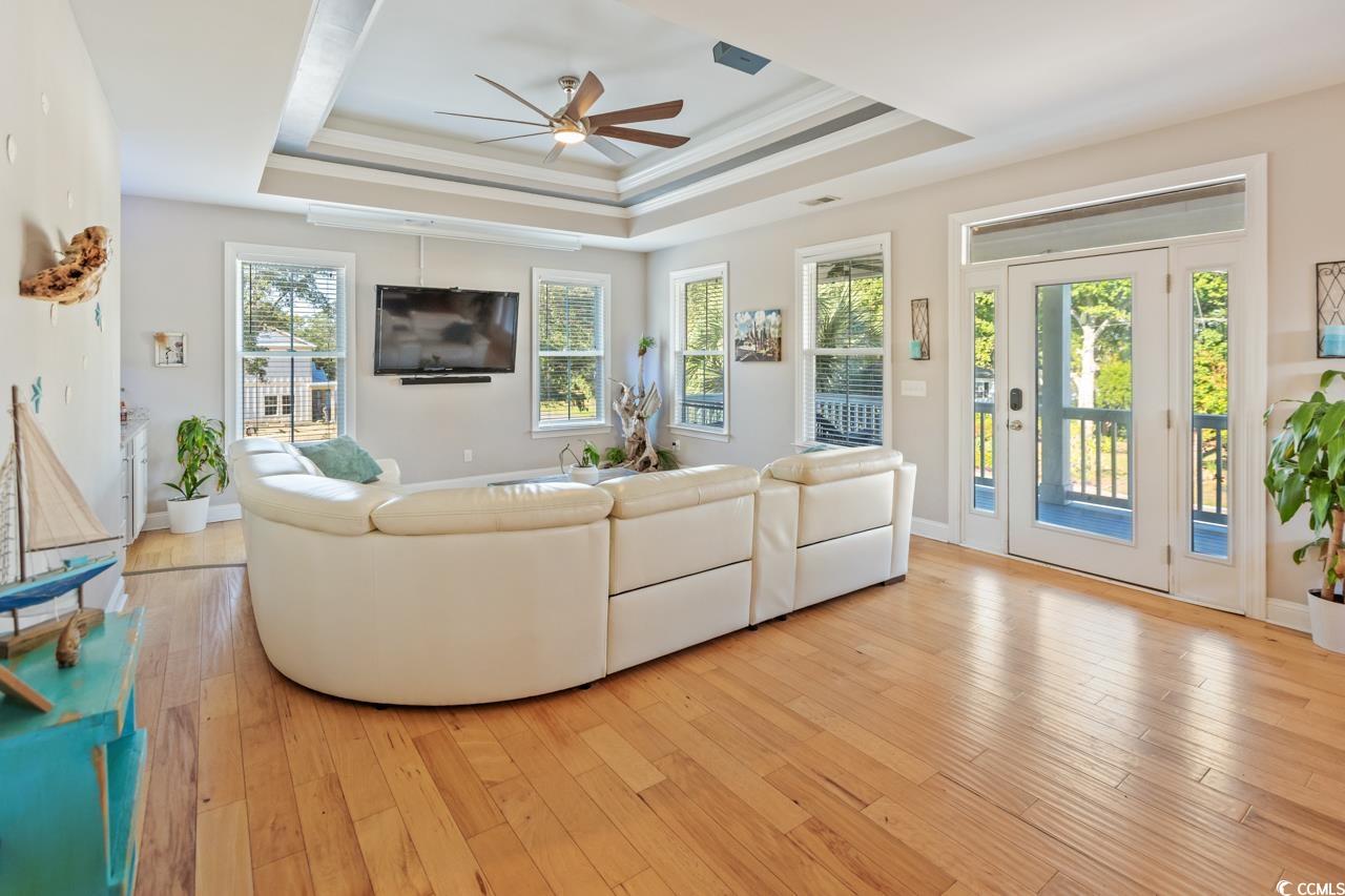 3887 Spanner Way Murrells Inlet, SC 29576 - Photo 12 of 32 Living area featuring a raised ceiling, light wood-style flooring, ceiling fan, and ornamental molding