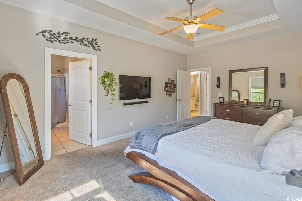 3887 Spanner Way Murrells Inlet, SC 29576 - Photo 16 of 32 Bedroom featuring a tray ceiling, light carpet, ornamental molding, ceiling fan, and ensuite bath
