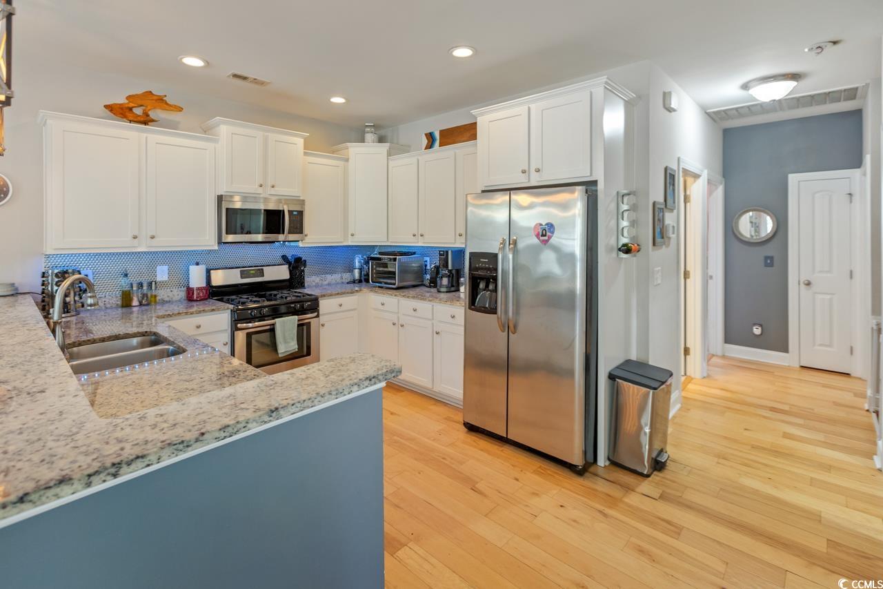 3887 Spanner Way Murrells Inlet, SC 29576 - Photo 10 of 32 Kitchen with white cabinets, light stone counters, stainless steel appliances, recessed lighting, and light wood-style flooring