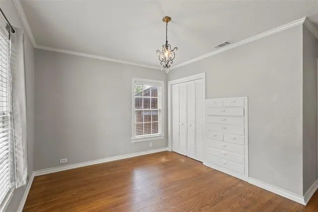 an empty room with wooden floor chandelier and windows
