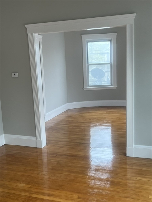 168 Brook Road, Unit 1 Milton, MA 02186 - Photo 11 of 13 a view of an empty room with wooden floor and a window