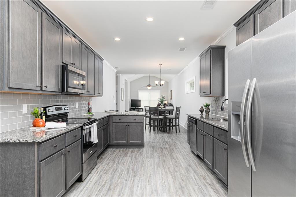 59 Calloway Lane Cartersville, GA 30120 - Photo 5 of 29 a kitchen with stainless steel appliances granite countertop a refrigerator a stove top oven a sink dishwasher and wooden cabinets with wooden floor