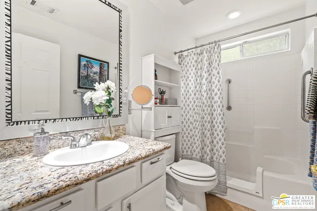 a bathroom with a granite countertop toilet a sink and a mirror