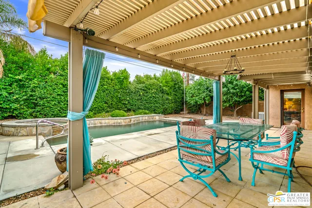 a view of a patio with table and chairs and wooden floor next to a yard