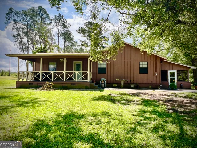 a front view of house with yard and trees in the background