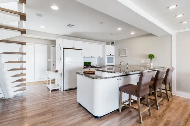 a kitchen with stainless steel appliances kitchen island granite countertop a table chairs and a refrigerator
